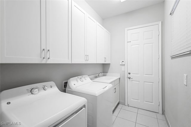 laundry area featuring light tile patterned flooring, washing machine and dryer, cabinets, and sink