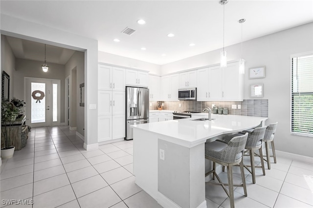 kitchen featuring stainless steel appliances, pendant lighting, white cabinets, and a kitchen bar