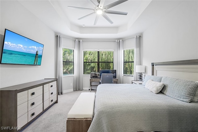 bedroom featuring ceiling fan, a raised ceiling, and light carpet