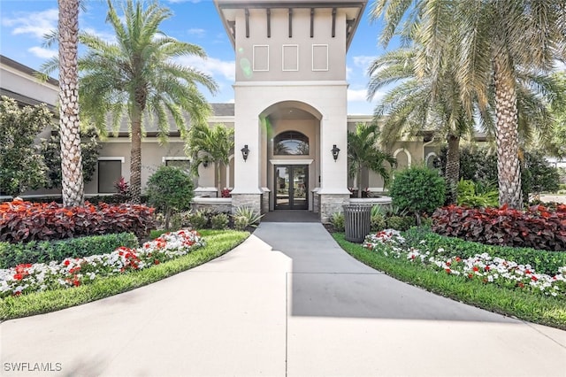 doorway to property with stone siding, french doors, and stucco siding