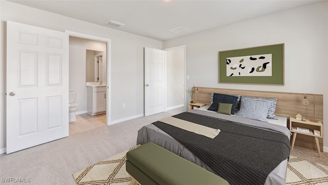 bedroom featuring connected bathroom and light colored carpet