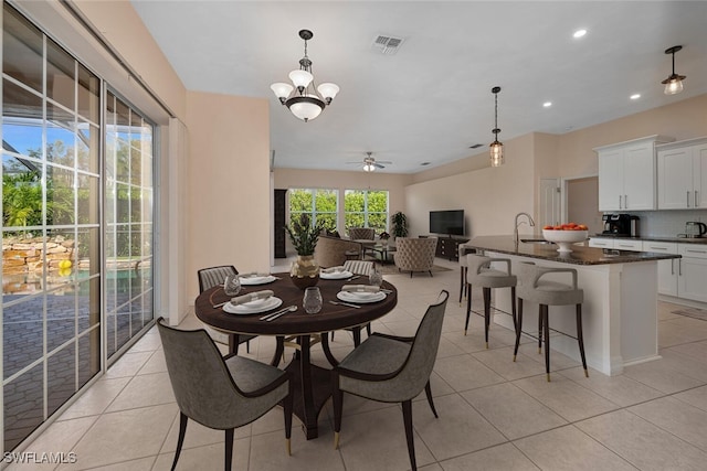 tiled dining area with ceiling fan with notable chandelier and sink