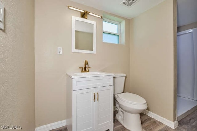 bathroom with hardwood / wood-style flooring, toilet, and vanity