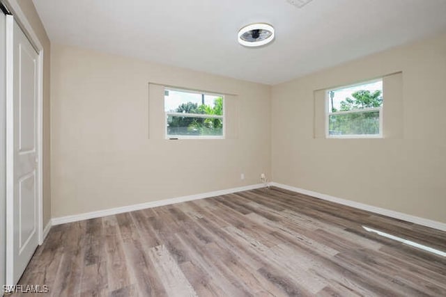 unfurnished bedroom with hardwood / wood-style flooring, multiple windows, and a closet