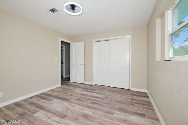 unfurnished bedroom featuring a closet and light wood-type flooring