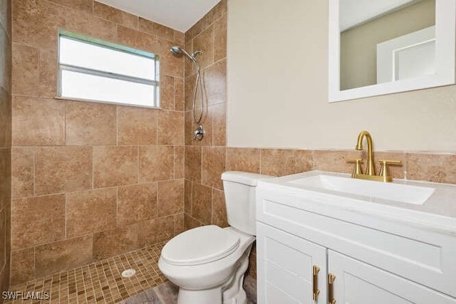 bathroom with tiled shower, vanity, and toilet