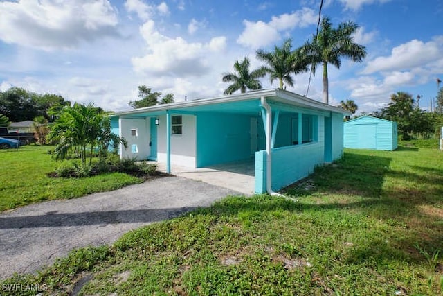 ranch-style home with a front lawn, a shed, and a carport