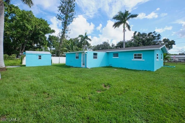 back of property with a yard and a storage unit