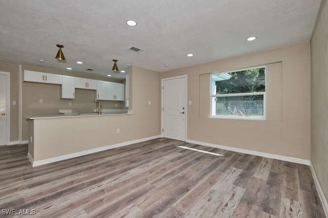 unfurnished living room featuring light hardwood / wood-style floors and a textured ceiling