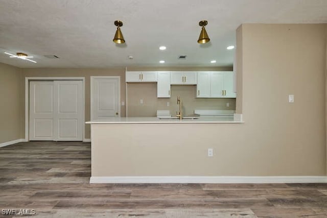 kitchen with pendant lighting, light hardwood / wood-style flooring, sink, and white cabinetry