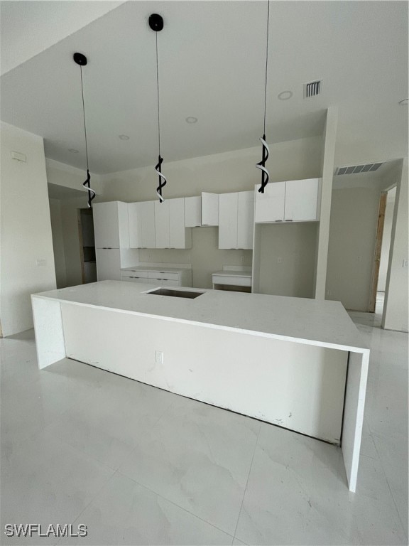 kitchen featuring hanging light fixtures, a center island, and white cabinetry