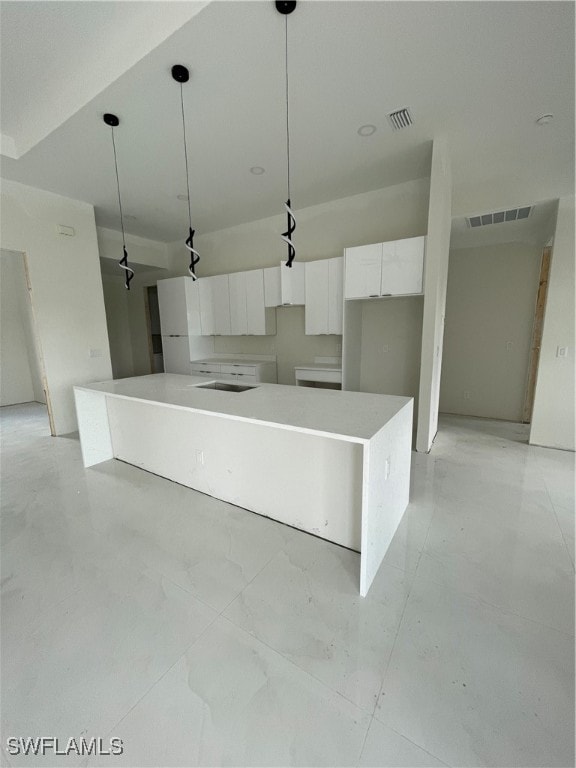 kitchen with a kitchen island, pendant lighting, and white cabinetry