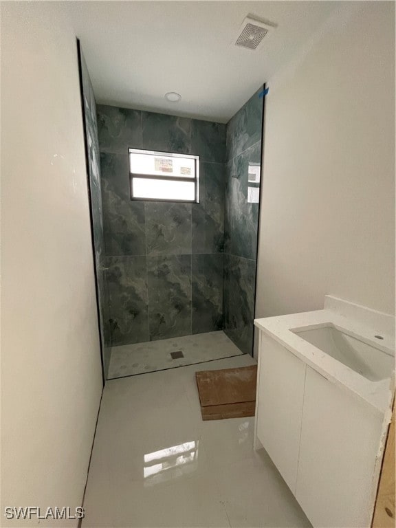 bathroom with a tile shower and vanity