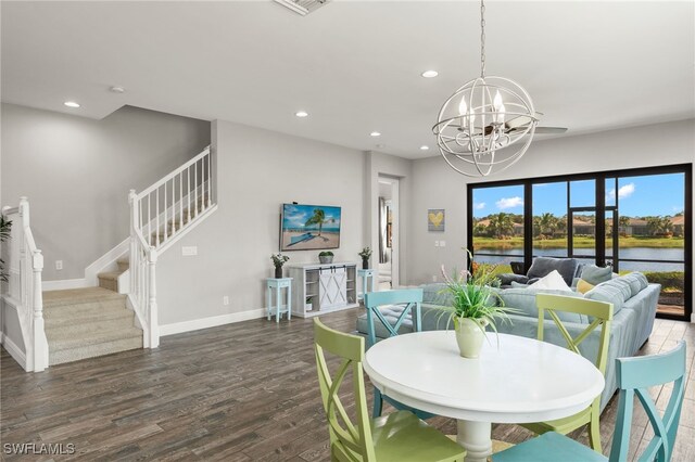 dining space featuring dark wood-type flooring, a chandelier, and a water view