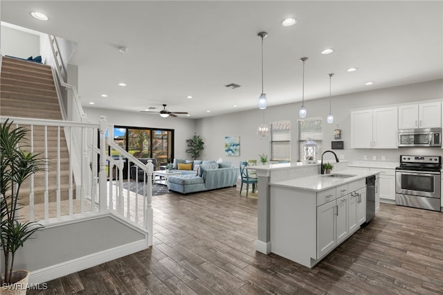 kitchen featuring stainless steel appliances, dark wood-type flooring, a sink, white cabinets, and light countertops