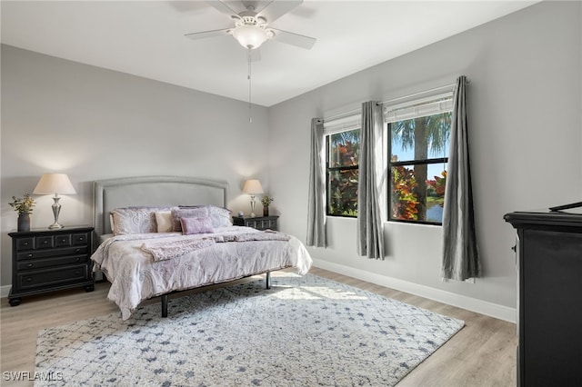 bedroom with light wood-style floors, ceiling fan, and baseboards