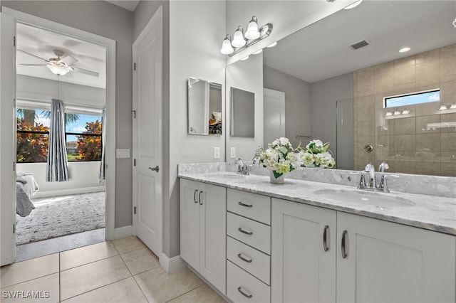 full bathroom featuring a tile shower, double vanity, tile patterned flooring, and a sink