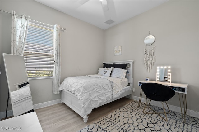 bedroom with ceiling fan, wood finished floors, visible vents, and baseboards