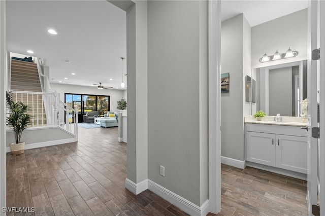 corridor with a sink, dark wood finished floors, and baseboards