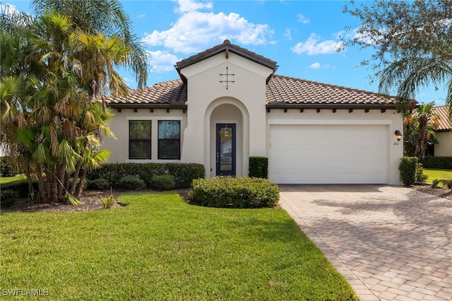 mediterranean / spanish-style home with decorative driveway, stucco siding, an attached garage, a tiled roof, and a front lawn