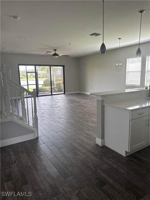 unfurnished living room featuring baseboards, visible vents, ceiling fan, and dark wood-style flooring