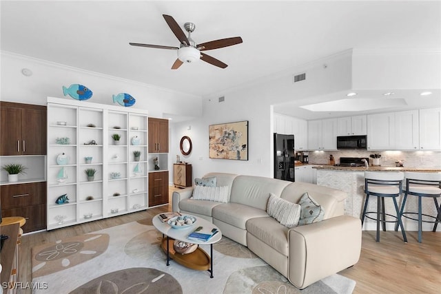 living room featuring crown molding, ceiling fan, and light wood-type flooring