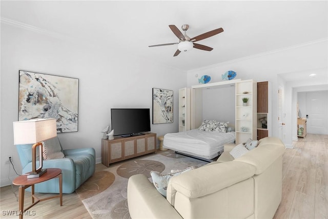 living room featuring ceiling fan, light wood-type flooring, and ornamental molding