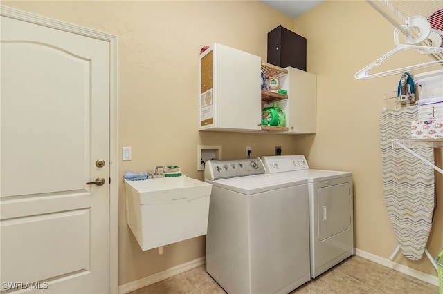 laundry area featuring light tile patterned floors, cabinets, sink, and washing machine and clothes dryer