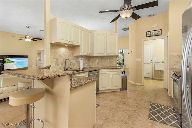 kitchen featuring a breakfast bar, dark stone countertops, sink, kitchen peninsula, and backsplash