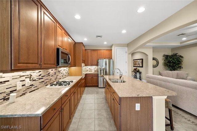 kitchen with tasteful backsplash, an island with sink, appliances with stainless steel finishes, a kitchen bar, and sink