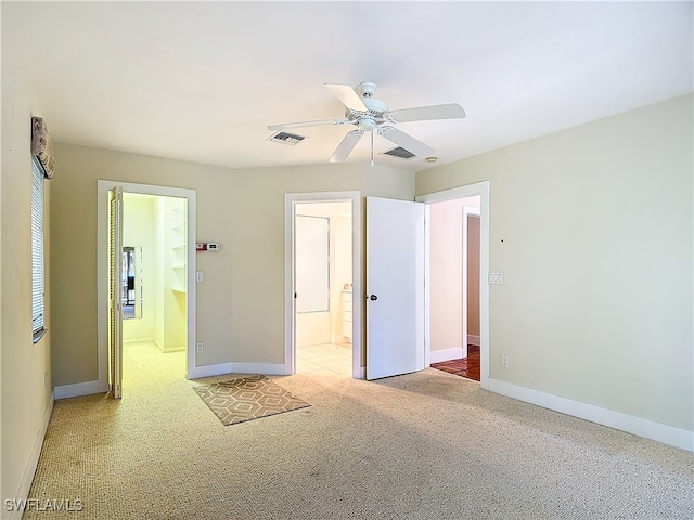 unfurnished bedroom with ceiling fan, ensuite bath, and carpet flooring