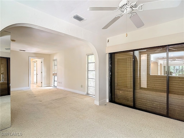 unfurnished room featuring ceiling fan, a wealth of natural light, and light colored carpet