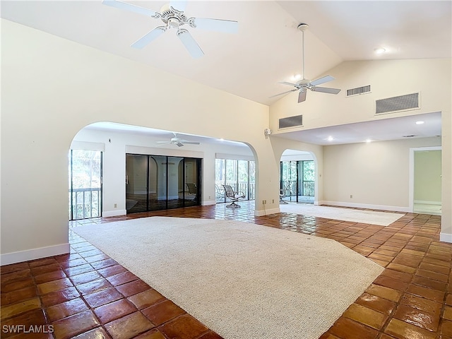 unfurnished living room with ceiling fan and high vaulted ceiling