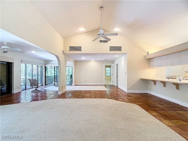 unfurnished living room featuring ceiling fan, high vaulted ceiling, and tile patterned flooring