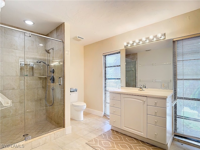 bathroom with tile patterned flooring, a shower with door, vanity, and toilet