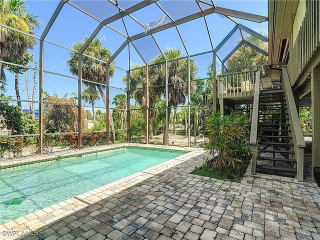 view of swimming pool with a patio area, a wooden deck, and a lanai