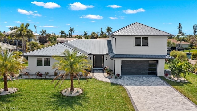 view of front of property featuring a garage, central AC unit, and a front yard