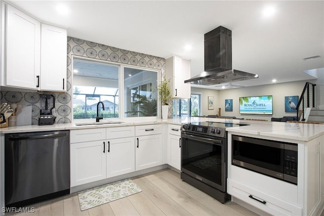 kitchen with sink, white cabinetry, stainless steel appliances, island range hood, and kitchen peninsula