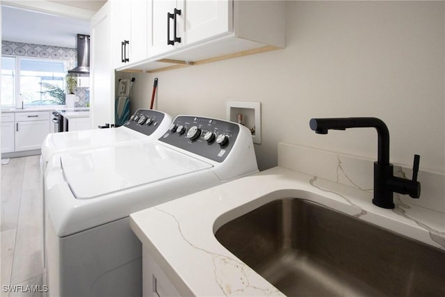 washroom with cabinets, light hardwood / wood-style floors, sink, and washing machine and dryer