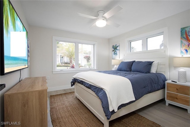 bedroom with multiple windows, dark hardwood / wood-style floors, and ceiling fan