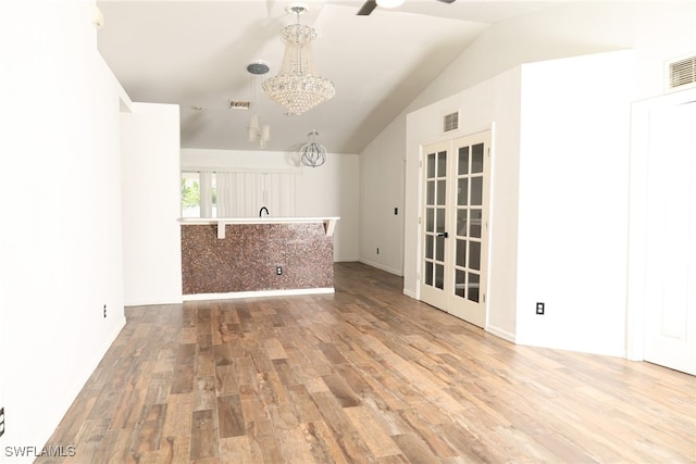 interior space with hardwood / wood-style floors, an inviting chandelier, and vaulted ceiling