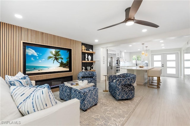 living room featuring ceiling fan, light hardwood / wood-style flooring, and french doors