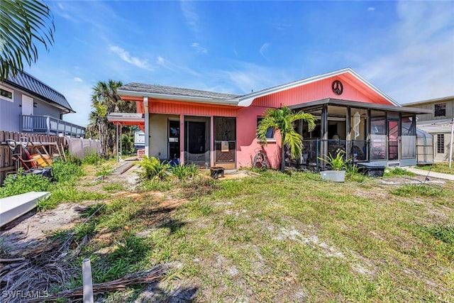 rear view of property with stucco siding, fence, a lawn, and a sunroom