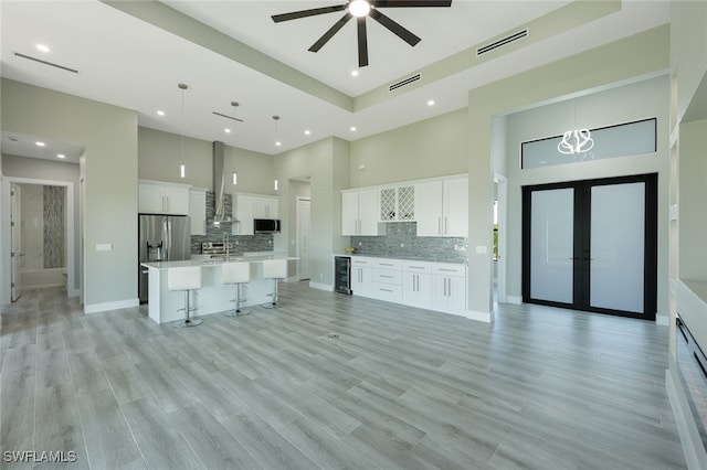 kitchen featuring visible vents, wine cooler, open floor plan, a high ceiling, and stainless steel appliances