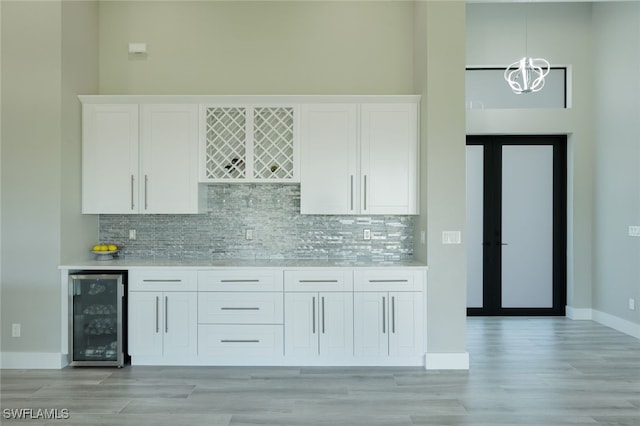 kitchen featuring decorative backsplash, light countertops, wine cooler, and white cabinets