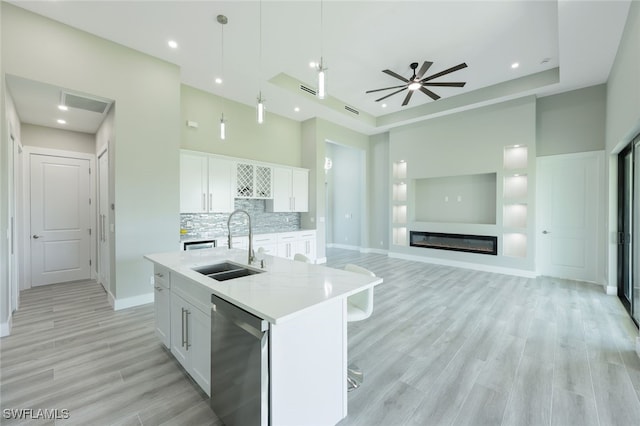 kitchen featuring a glass covered fireplace, white cabinetry, a sink, light countertops, and stainless steel dishwasher