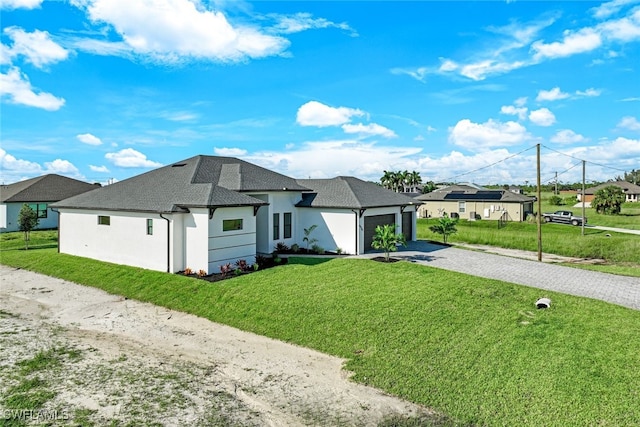 view of front of house with stucco siding, driveway, a shingled roof, a front yard, and an attached garage