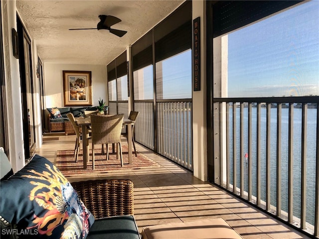 sunroom featuring a water view and ceiling fan