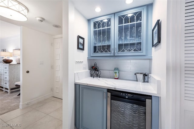 bar featuring backsplash, light stone countertops, beverage cooler, and light tile patterned flooring