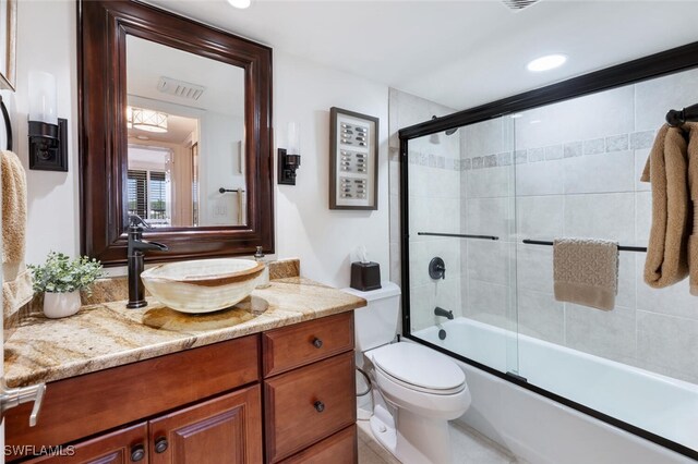 full bathroom featuring vanity, shower / bath combination with glass door, and toilet